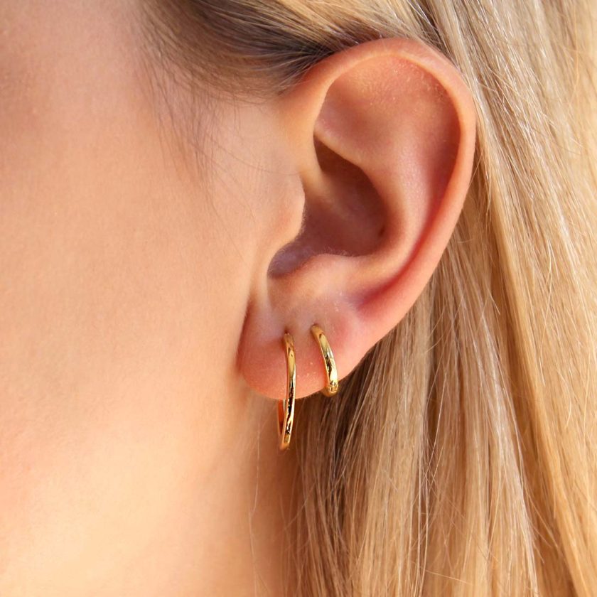 combinacion de argollas doradas en oreja de joven mujer