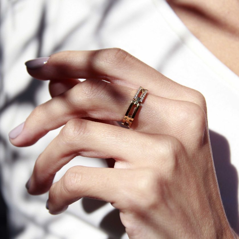 manos de mujer con anillo dorado de diseño calado y detalle de brillantes